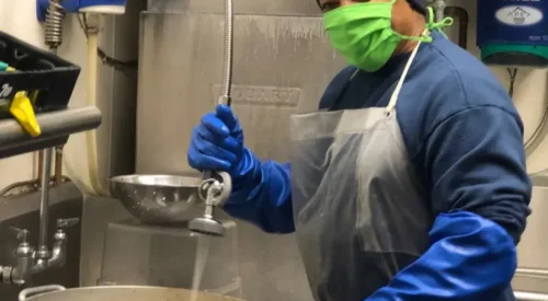 Man washing dishes and wearing mask