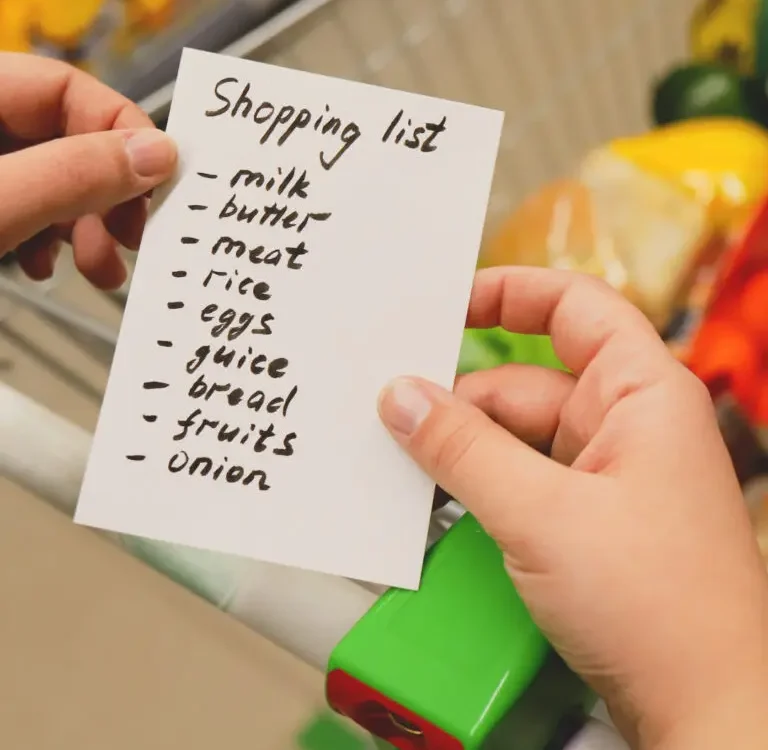Person holds a shopping list with list of groceries