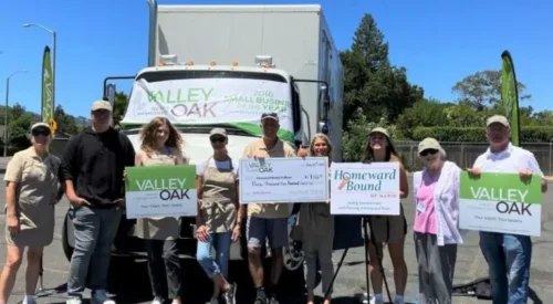 Group of people standing in front of shredding truck. One holds an oversize check for $9,926 raised at the Big Shred.