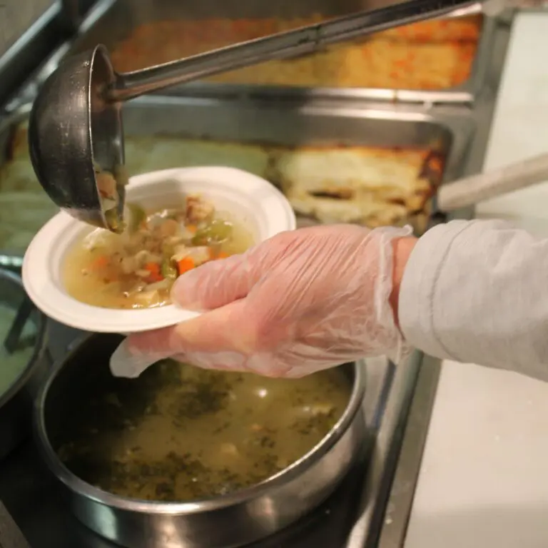 Server ladles soup into a bowl