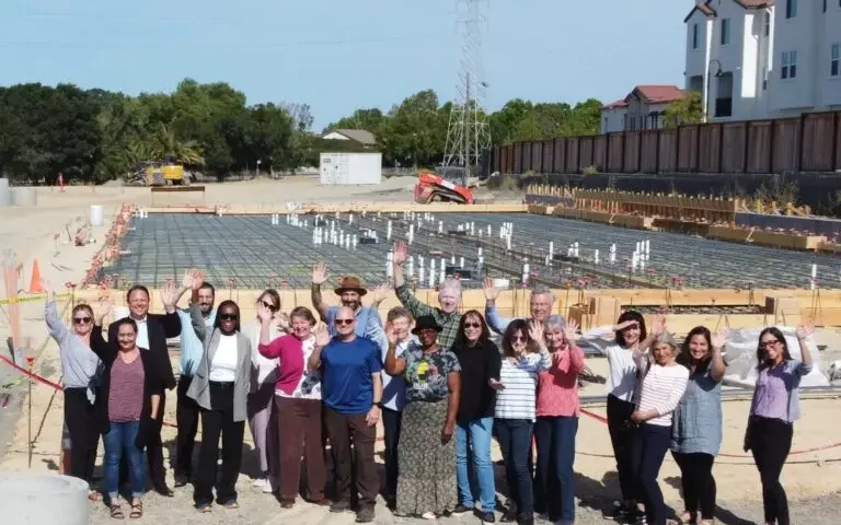 a group of people waving in front of a foundation of a building
