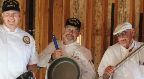 three men holding cooking tools