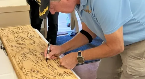 a man signing a note on a wooden board