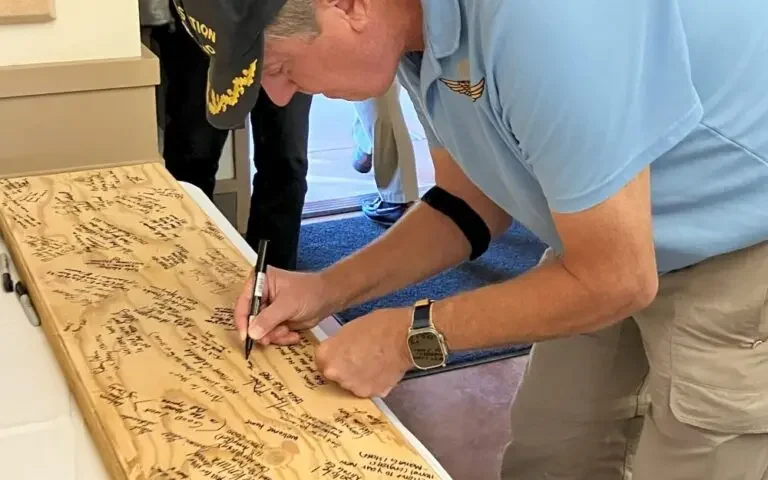 a man signing a note on a wooden board