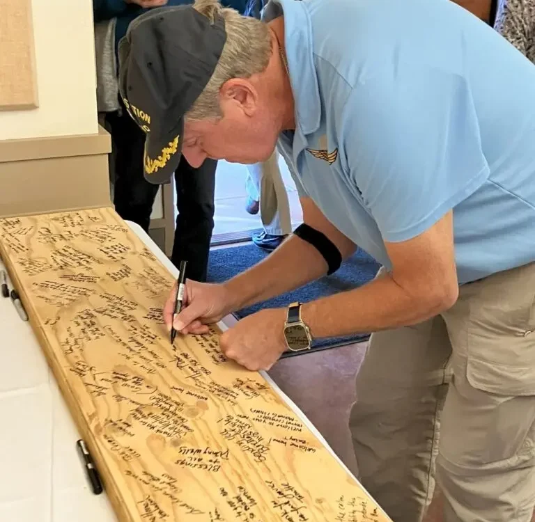 a man signing a note on a wooden board