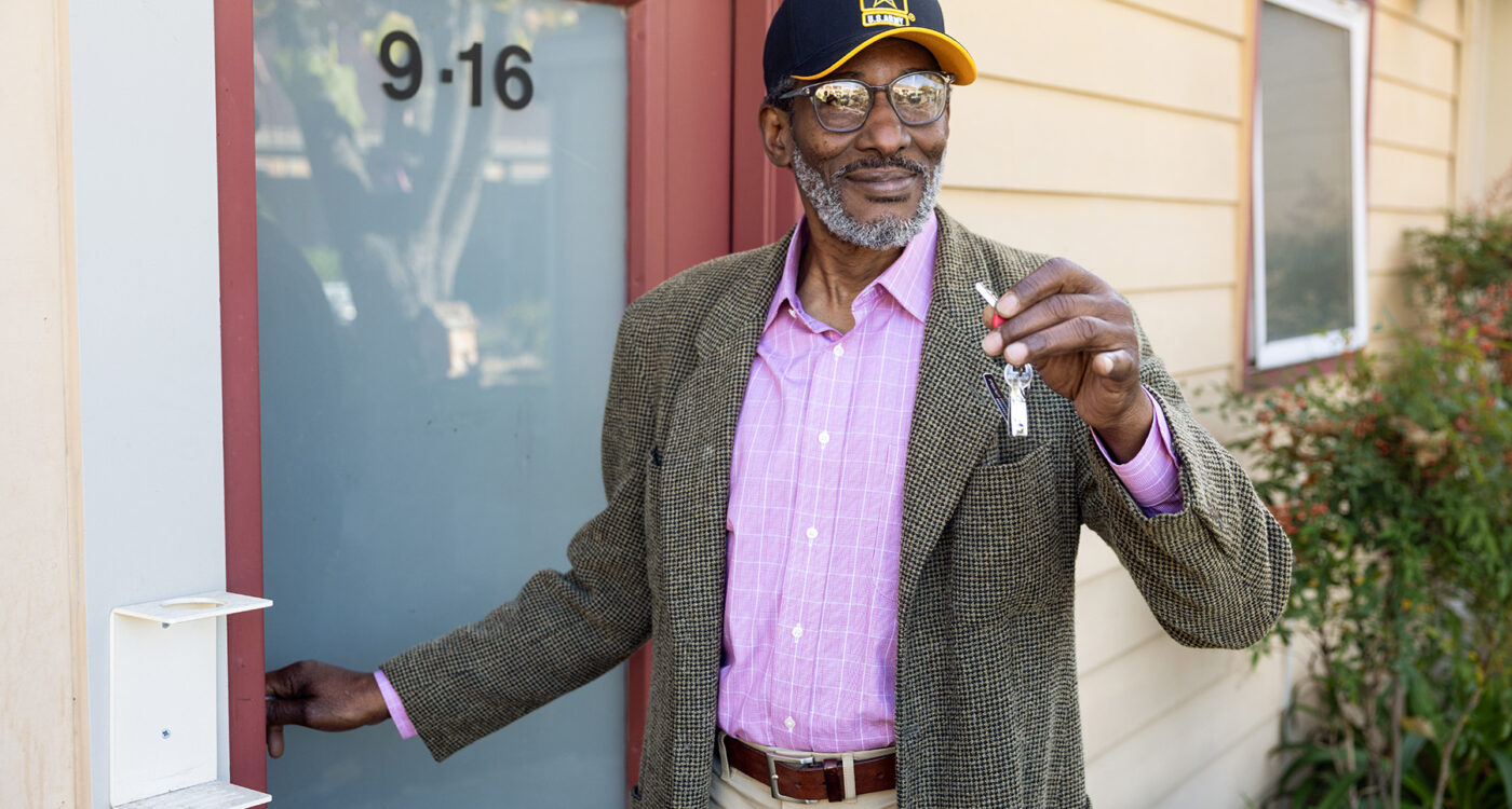 a veteran stands in front of a door showing his key