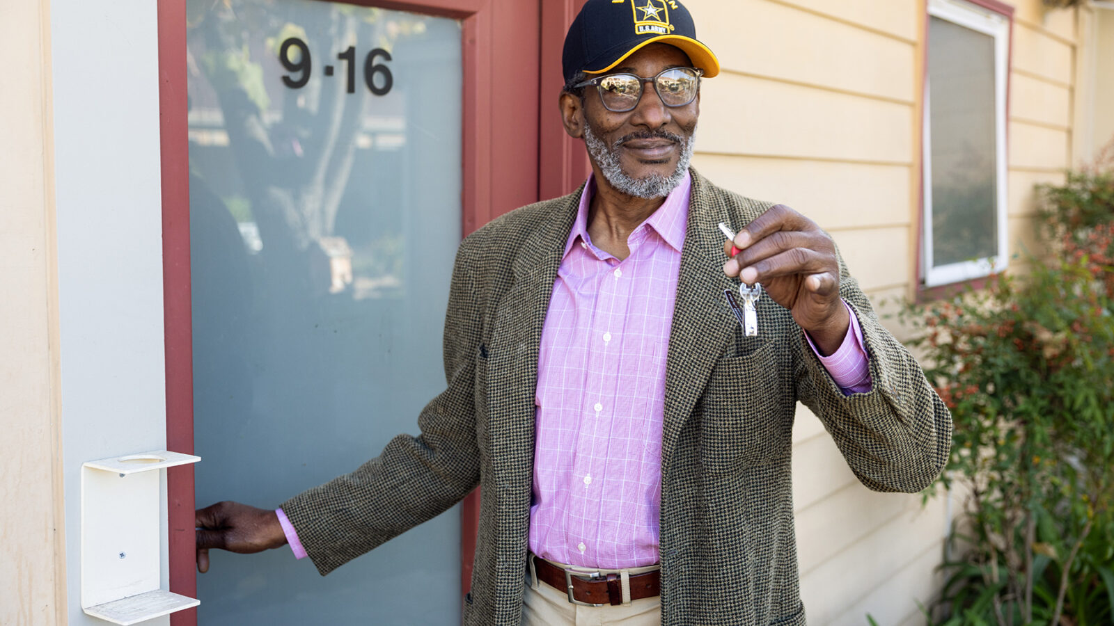 a veteran stands in front of a door showing his key