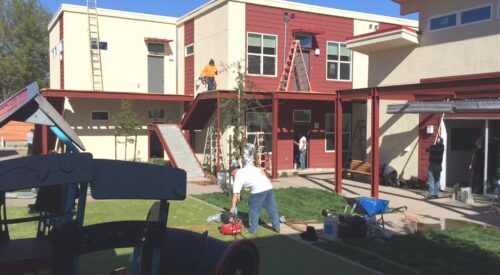 Oma Village apartment building with courtyard and workers preparing for the opening