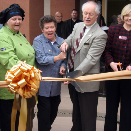 4 people, including Mary Kay Sweeney, cutting a ribbon outside The Next Key Center.