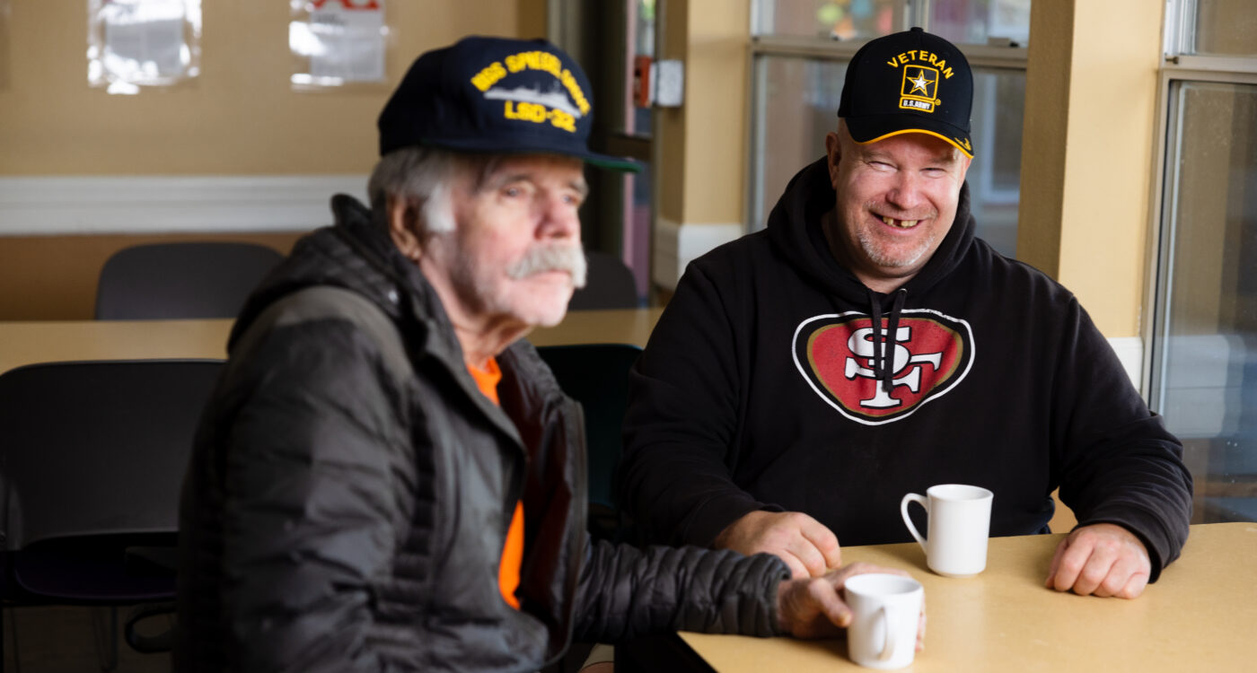two veterans sit a a table with coffee mugs