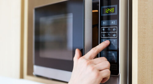 a hand pressing buttons on a microwave