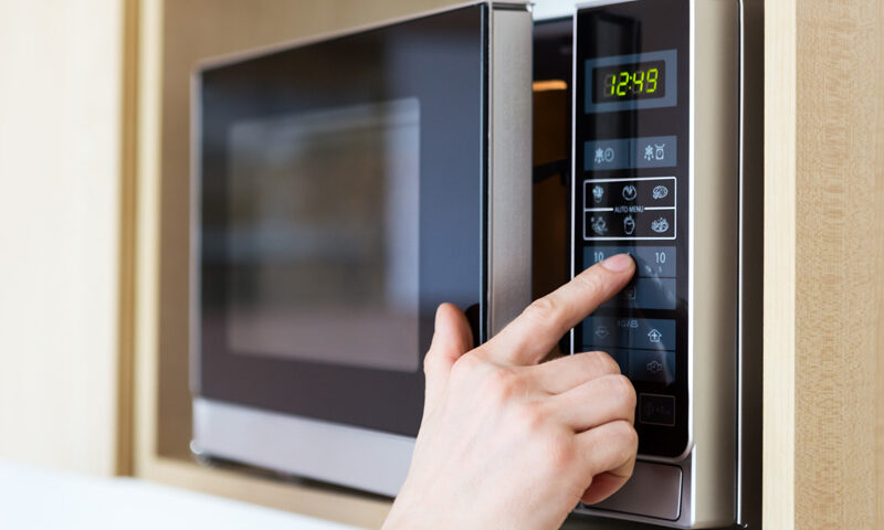 a hand pressing buttons on a microwave