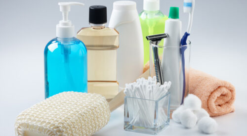 bottles of soaps and shampoos, a scrub brush, q-tips, cotton balls, toothbrush and paste, a razor and cloth.