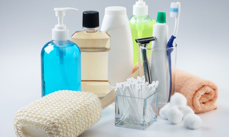 bottles of soaps and shampoos, a scrub brush, q-tips, cotton balls, toothbrush and paste, a razor and cloth.