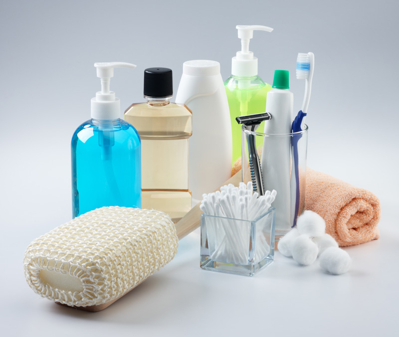 bottles of soaps and shampoos, a scrub brush, q-tips, cotton balls, toothbrush and paste, a razor and cloth.