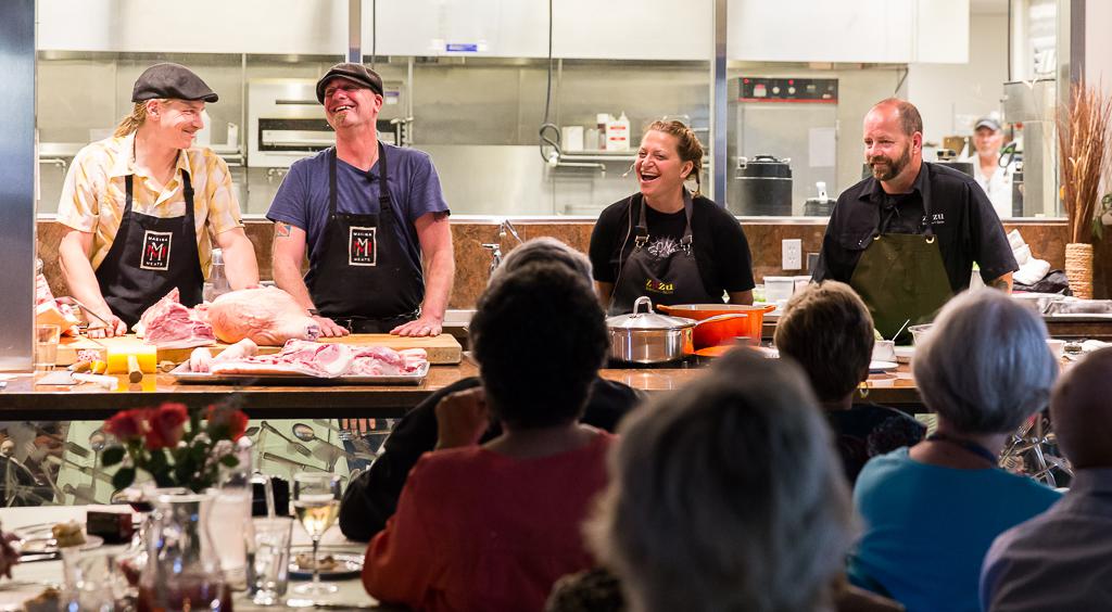 Four chefs laughing and standing in front of an audience