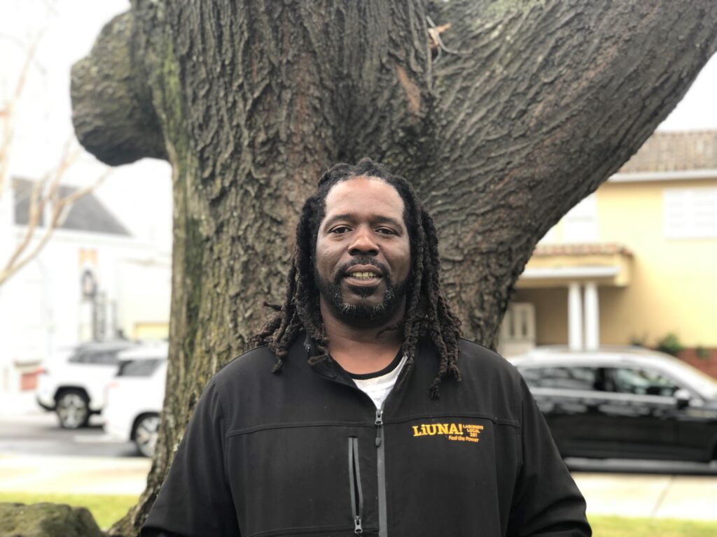 Antonio smiling and standing in front of a tree