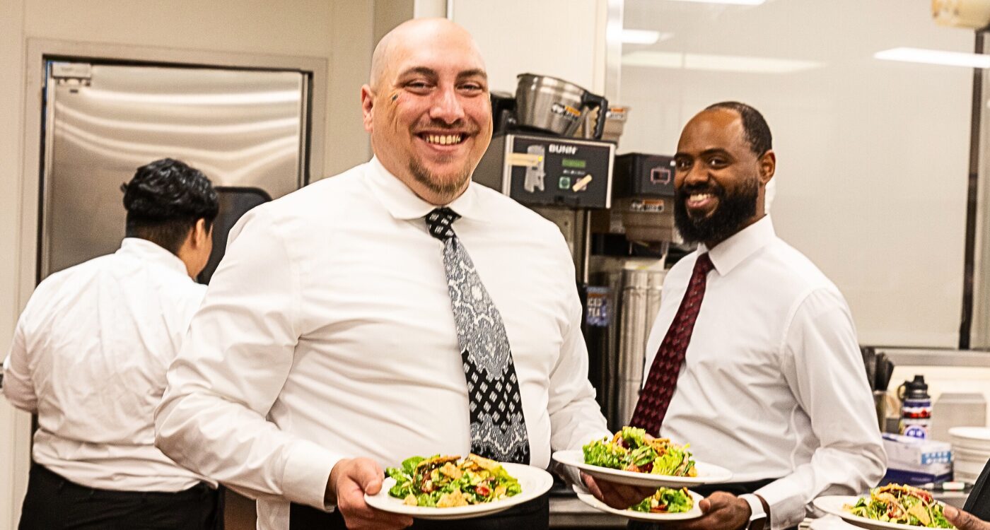 Two chefs in the Fresh Starts Culinary Academy prepare plates of food