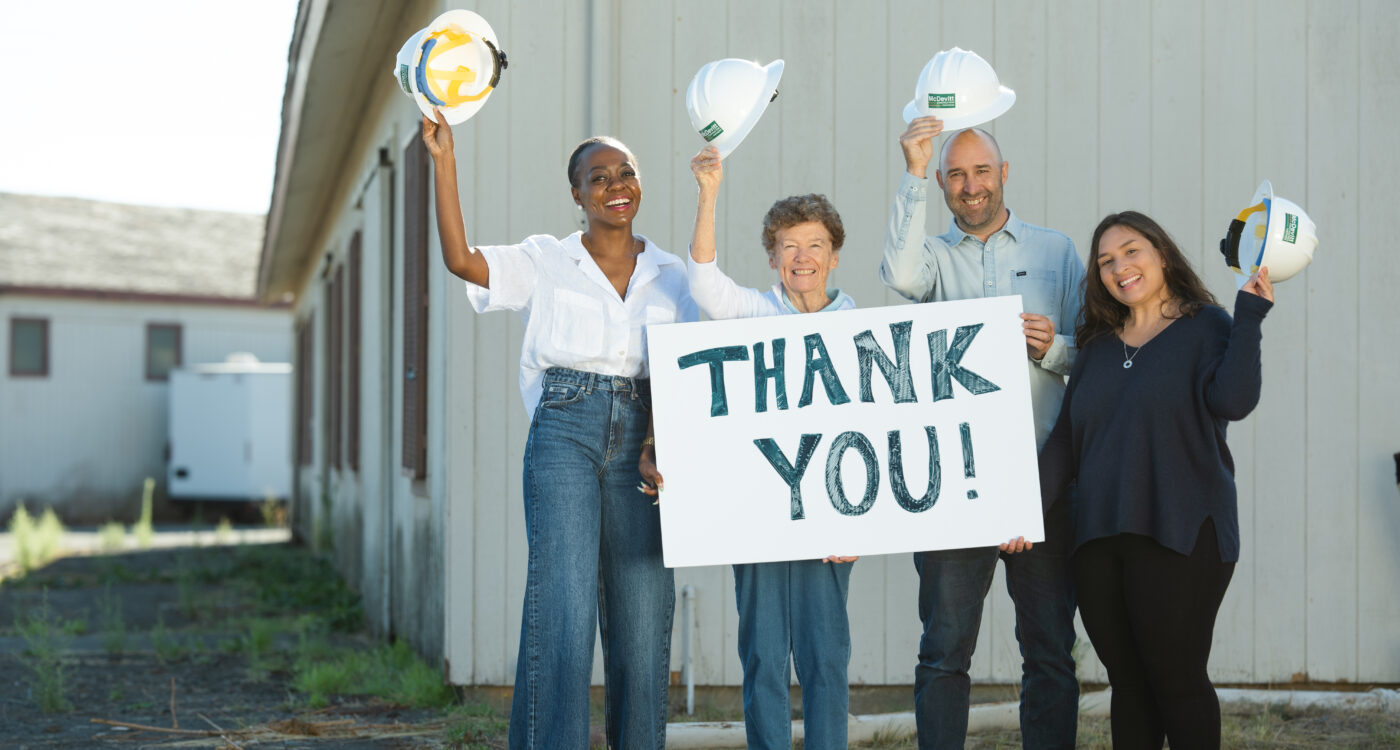 four people holding hard hats and a "thank you" sign