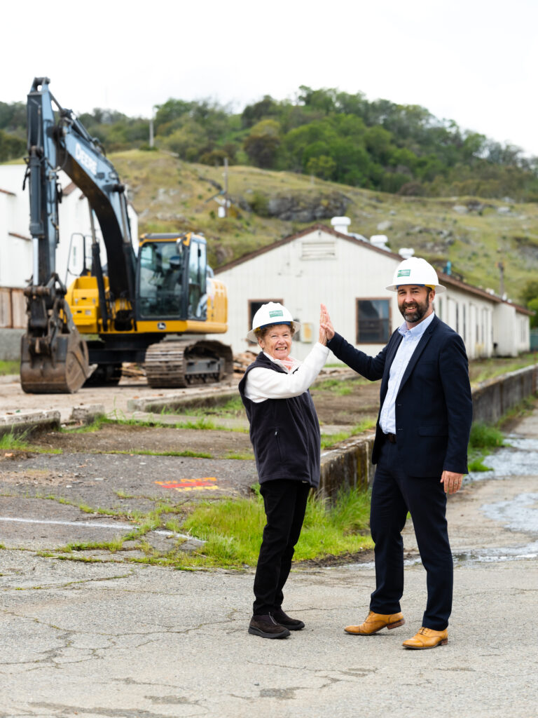 two people high-fiving in front of a construction site