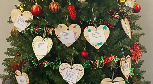 Tree with ornaments that have paper message stating a gift wish from a family at Homeward Bound of Marin.