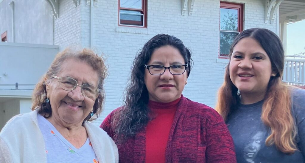 Grandmother, mother and daughter stand outside Fireside Apartments.