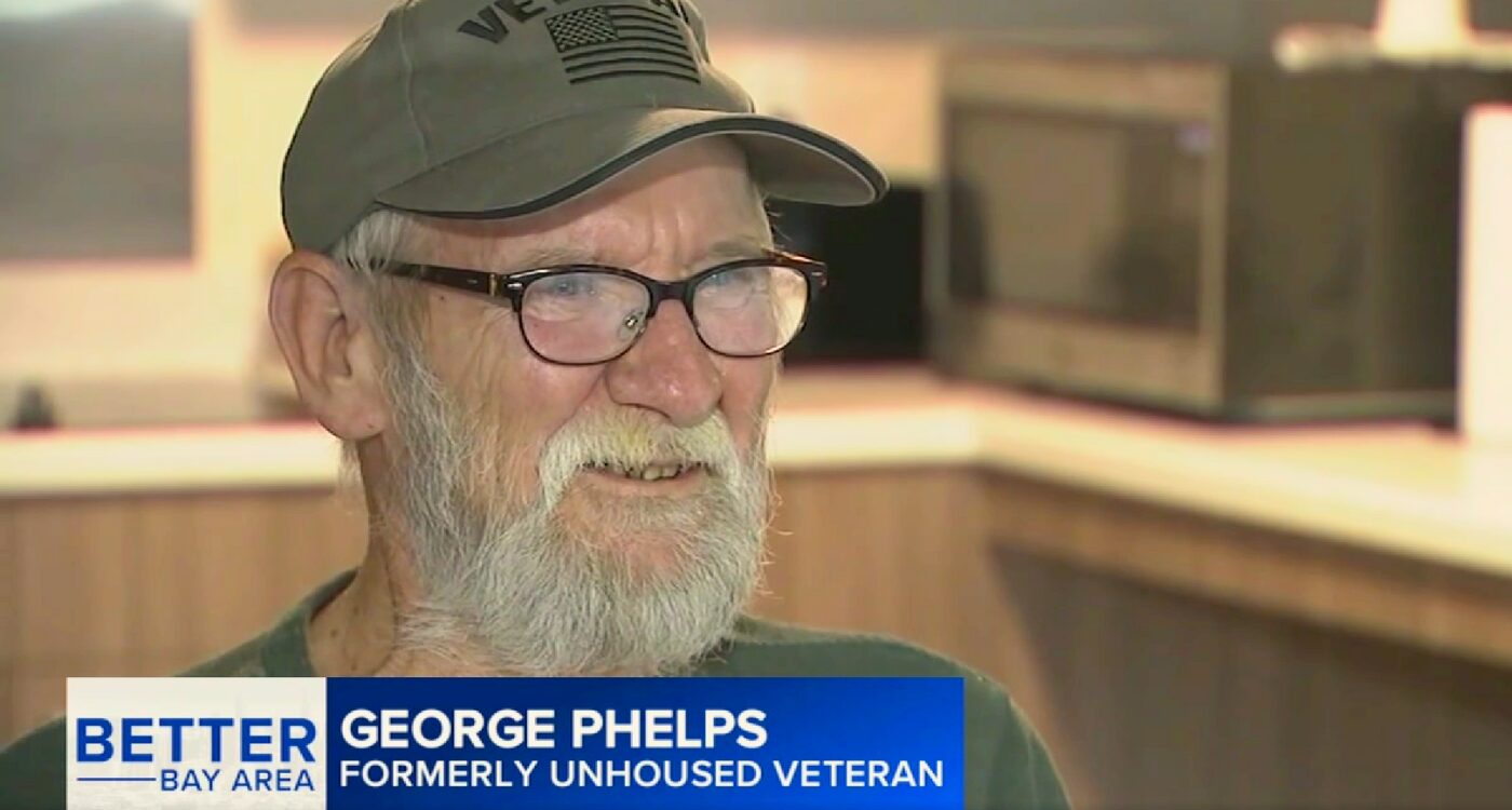 Man with beard and glasses sits in his apartment kitchen.