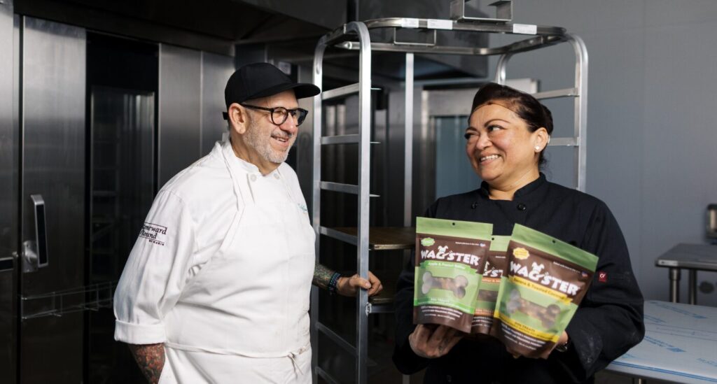 Chef in white coat and baker in black jacket stand in new bakery.