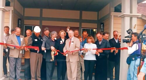 Men and women in business attire cut the ribbon at the New Beginnings Center doorway.