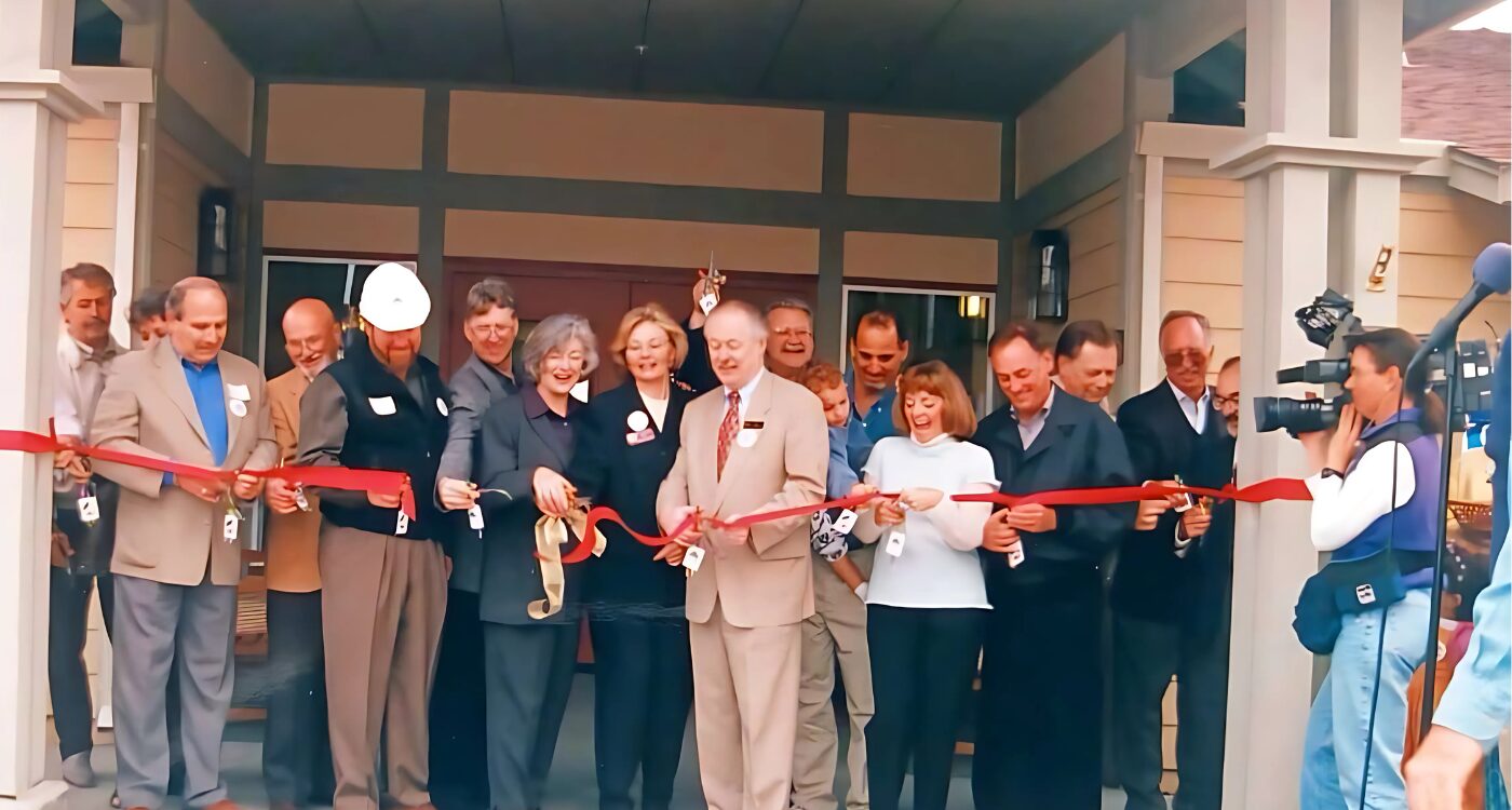 Men and women in business attire cut the ribbon at the New Beginnings Center doorway.