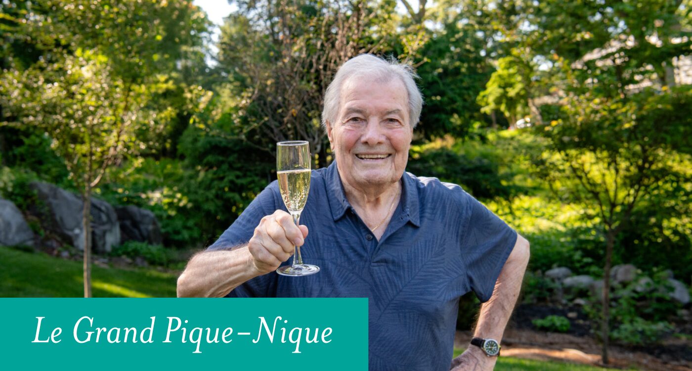 Man standing in a garden lifts glass of champagne.