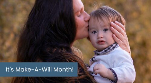Woman with long dark hair holds a toddler and kisses his cheek.