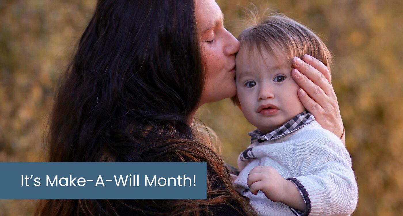 Woman with long dark hair holds a toddler and kisses his cheek.