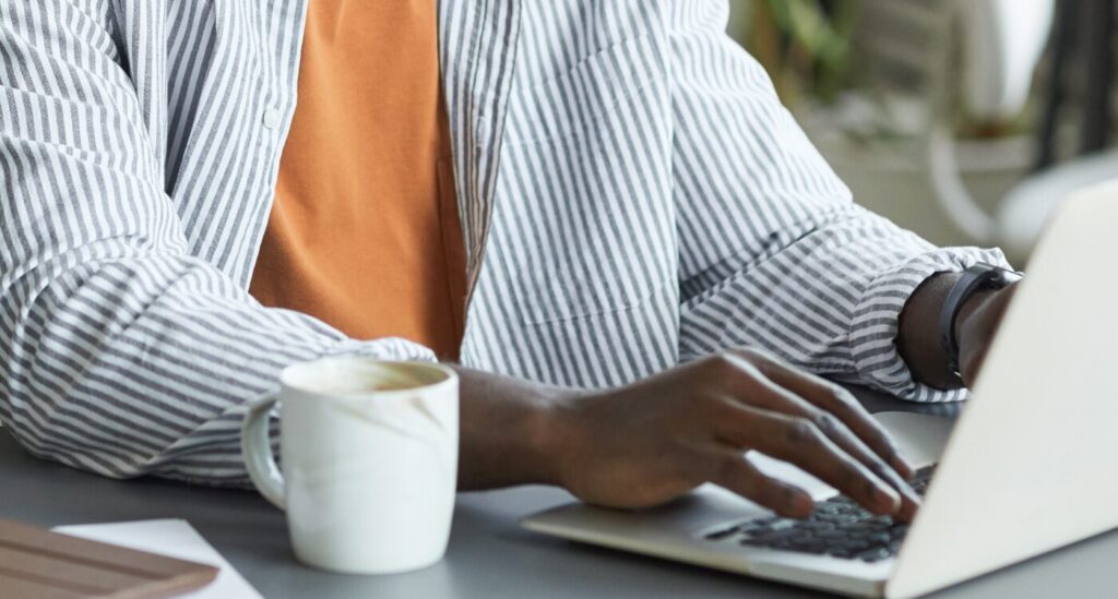 Man's hands type on computer keyboard