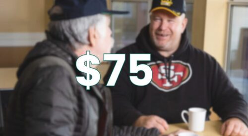 Two men with veteran hats talking at a table