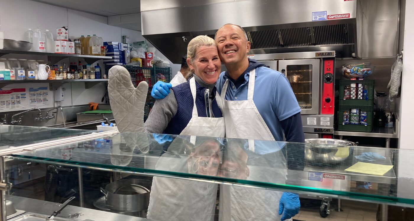 Man and woman wearing aprons and oven mitts in a kitchen