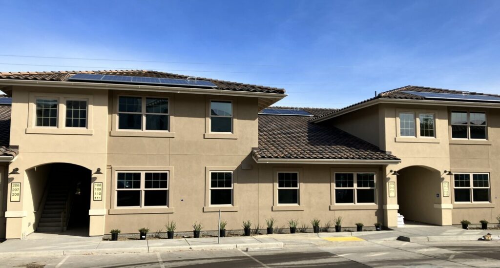 New two-story building with solar panels on roof and stucco exterior